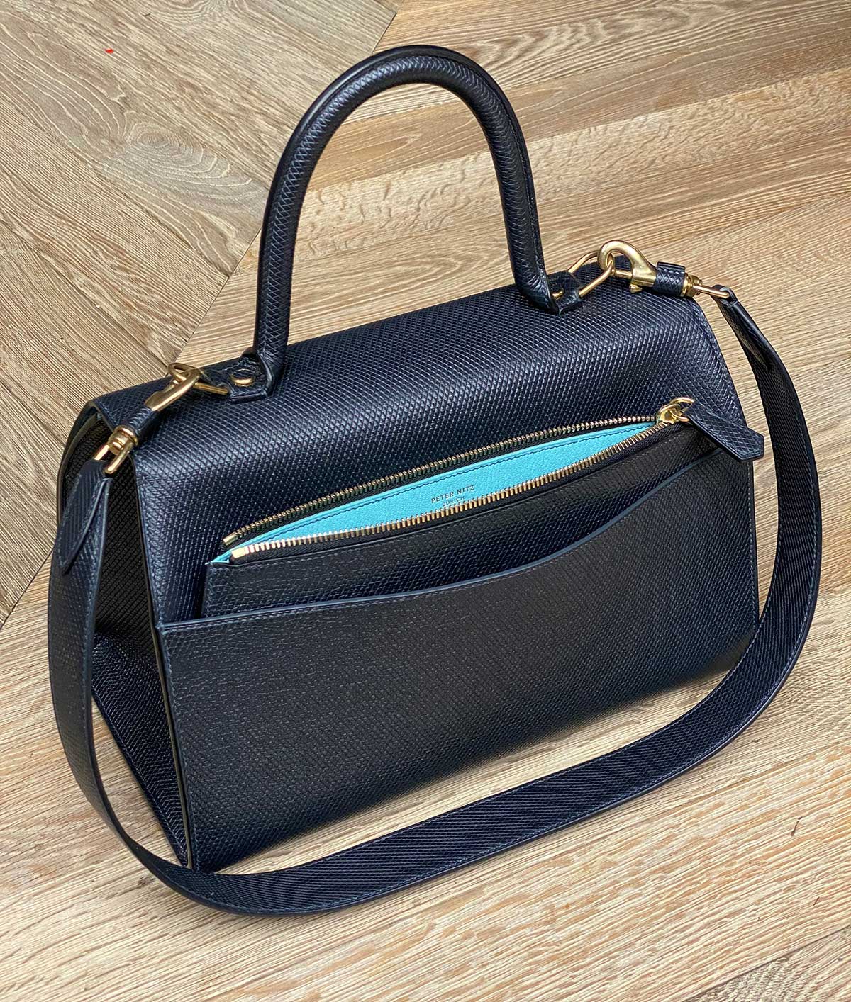 the back zipper detail of the back of the lorin black leather flap bag