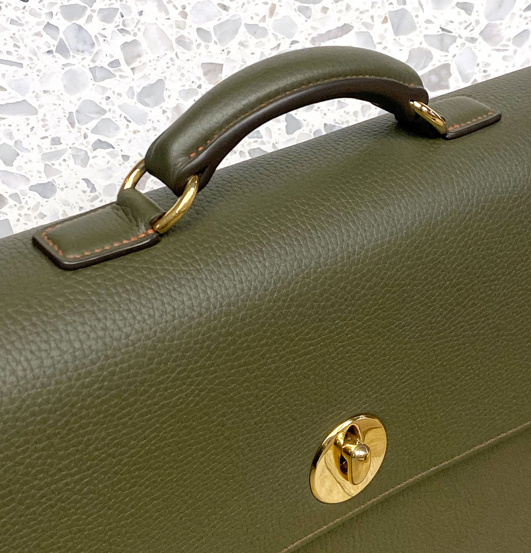 Close up of the olive green hackney briefcase with gold hardware closure