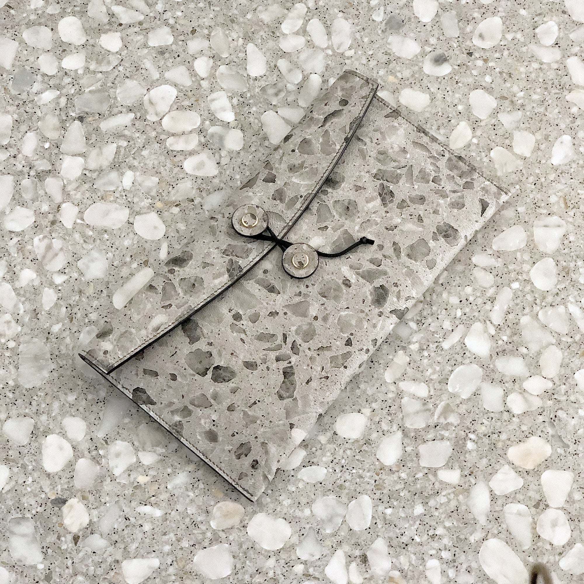 A terrazzo tether pouch laying on a terrazzo marble surface