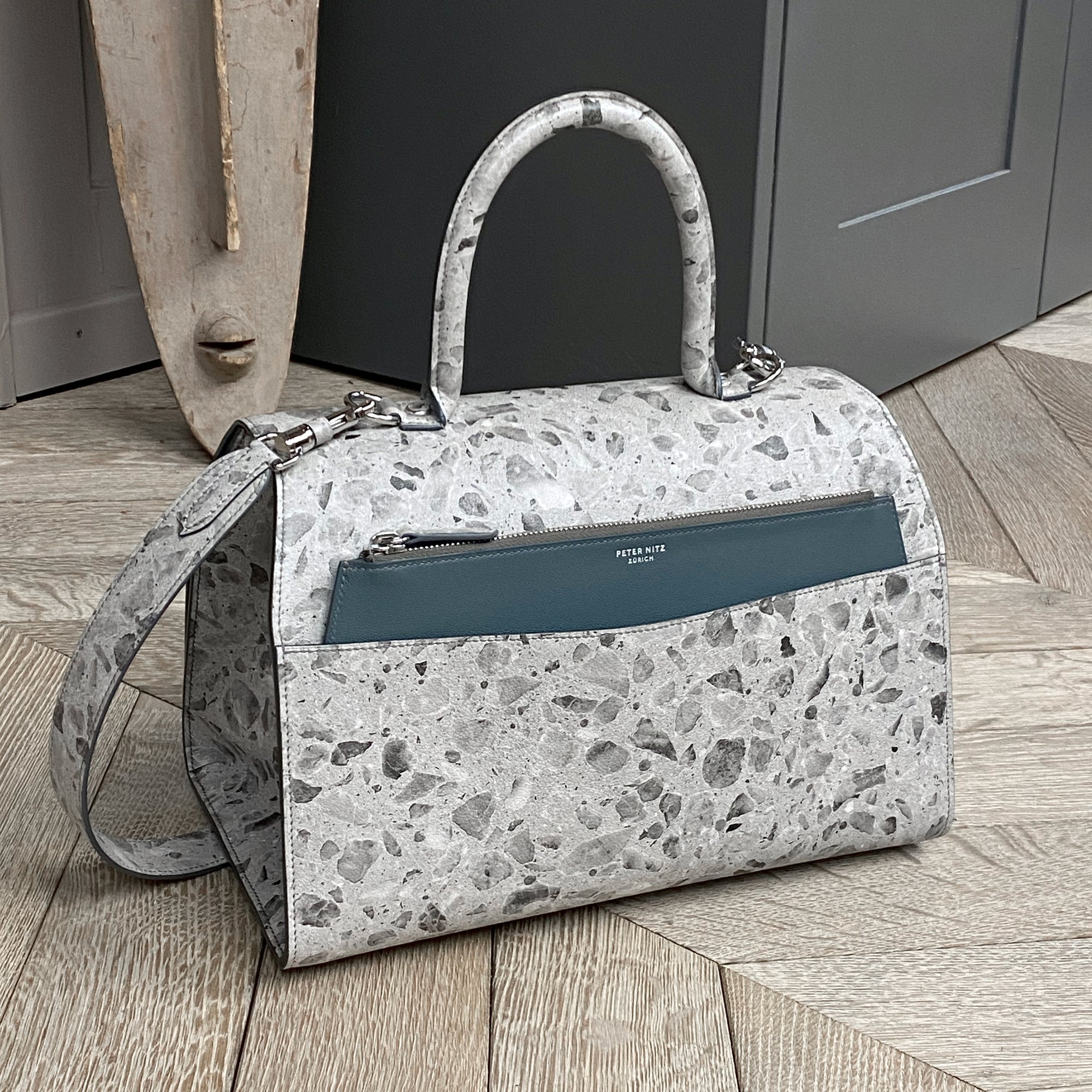the back of the lorin flap bag in terrazzo calf with a teal zip pouch